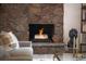 Stone fireplace with a lit fire, complementing the cozy ambiance of the home at 10000 E Ohio Ave, Denver, CO 80247