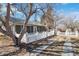 A view of the side of the home with a long screened-in porch with a concrete walkway and mature landscaping at 6025 S Sycamore St, Littleton, CO 80120