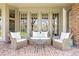 Inviting covered patio with cushioned wicker furniture on a classic brick floor at 21 Huntwick Ln, Cherry Hills Village, CO 80113