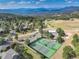 Aerial view of community tennis courts with mountain views in a wooded neighborhood at 23495 Bluestem Dr, Golden, CO 80401