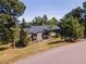 Charming exterior of the home with mature trees and a well-manicured lawn at 23495 Bluestem Dr, Golden, CO 80401