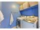 Efficient laundry room with modern washer/dryer, shelving, and blue painted walls at 23495 Bluestem Dr, Golden, CO 80401