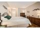 Neutral bedroom features a queen-size bed with white bedding, warm toned wood floors, and bright lighting at 8465 S Holland Way # 101, Littleton, CO 80128