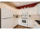 A well-lit kitchen with white cabinets, appliances, and contrasting red accent wall at 8465 S Holland Way # 101, Littleton, CO 80128