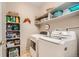 Bright laundry room with front loading washer and dryer, built in shelving, and tile flooring at 8465 S Holland Way # 101, Littleton, CO 80128