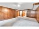 Spacious carpeted basement with paneled walls, built-in shelves and staircase leading to other levels at 3444 S Bellaire St, Denver, CO 80222