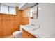 Bathroom with wooden paneled walls, white tiles and sink with window offering natural lighting at 3444 S Bellaire St, Denver, CO 80222