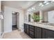Bathroom with dual sinks, dark cabinets, granite countertops, large mirrors, and walk-in closet at 3611 S Perth Cir # 103, Aurora, CO 80013