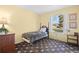 Bright bedroom featuring a floral patterned carpet, cheery yellow walls, and a sunny window view at 2608 E Fremont Pl, Centennial, CO 80122