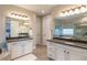 Bright bathroom featuring double vanity with dark countertop and classic white cabinets, plus a view into the bedroom at 11890 Discovery Cir, Parker, CO 80138