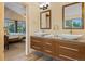 Modern bathroom featuring double sinks, a wood vanity, and views into the main bedroom at 4530 Ridgewood Ct, Castle Rock, CO 80109