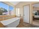 Modern bathroom with a freestanding tub, wood-look floors, and large window at 4530 Ridgewood Ct, Castle Rock, CO 80109