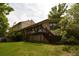 A lovely backyard view of the home, with deck, green lawn, and mature trees at 8130 E Bethany Pl, Denver, CO 80231