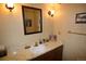 Traditional bathroom with a single sink vanity, gold fixtures, and framed art on the walls at 8130 E Bethany Pl, Denver, CO 80231