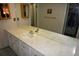 Bathroom featuring a double vanity with white cabinets, gold fixtures, and a large mirror at 8130 E Bethany Pl, Denver, CO 80231