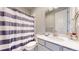 Bathroom with striped shower curtain, toilet, vanity, and large mirror with lighting at 12828 Fox Ct, Westminster, CO 80234