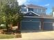 Two-story home featuring a three-car garage, blue siding, brick accents, and a mature tree at 2105 Keota Ln, Superior, CO 80027