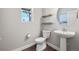 Modern half bathroom with a pedestal sink, toilet, and decorative floating wood shelves at 1632 Saddlesmith Pl, Castle Pines, CO 80108