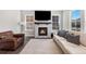 Bright living room with a cozy fireplace, large windows, and comfortable sectional at 1632 Saddlesmith Pl, Castle Pines, CO 80108