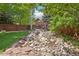 Landscaped backyard featuring a decorative rock garden with lush greenery and mature trees at 5046 Sage Brush Dr, Broomfield, CO 80023