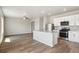 Modern kitchen featuring stainless steel appliances, a center island, and hardwood floors with an open concept to living area at 48250 Shetland Dr, Bennett, CO 80102