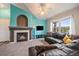 Bright living room with a fireplace, teal accent wall, ceiling fan, plush carpet, and a large window for natural light at 12931 Ironstone Way # 303, Parker, CO 80134
