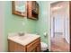 Bathroom with green walls, wood cabinets, and a view to another room through the open door at 1140 S Xavier St, Denver, CO 80219