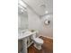 Cozy bathroom features a pedestal sink, decorative mirror, and a clean, white toilet and offers a warm, inviting space at 3195 Blake St # 106, Denver, CO 80205