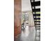Bright living room with modern staircase, large glass doors leading to an outdoor patio, and sleek concrete floors at 3195 Blake St # 106, Denver, CO 80205