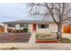 Charming single-story home featuring a well-maintained front yard, trimmed bushes, and a vibrant red front door at 1056 S Macon Way, Aurora, CO 80012