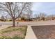 Street view of a house on a corner lot showing a tree in the front yard, sidewalk, and street at 1056 S Macon Way, Aurora, CO 80012