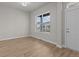Empty room featuring hardwood floors, neutral walls, a large window, and a door, creating a bright and airy space at 21202 E 63Rd Dr, Aurora, CO 80019