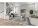 Contemporary living room featuring modern furnishings, a neutral color palette, and hardwood floors, next to the stairs at 21202 E 63Rd Dr, Aurora, CO 80019