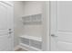 Bright mudroom featuring white shelving, hooks, and a built-in bench for efficient organization at 21202 E 63Rd Dr, Aurora, CO 80019