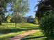 A view from the yard overlooking a grassy area with mature trees, and walking paths at 7641 S Rosemary Cir, Centennial, CO 80112
