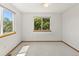 Bright bedroom with neutral carpet and trim featuring a large window with wooded view at 14185 W Warren Cir, Lakewood, CO 80228