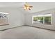 Primary bedroom features light carpet, ceiling fan, and large bright windows at 14185 W Warren Cir, Lakewood, CO 80228