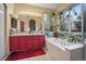 Bright bathroom with a large mirror, vanity with red cabinets, soaking tub, and large window with climbing plants at 6581 W Alamo Dr, Littleton, CO 80123