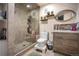 Bathroom featuring a tile shower with glass door, toilet, and vanity with wood-look drawers and an oval mirror at 6581 W Alamo Dr, Littleton, CO 80123