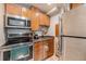 Compact kitchen with stainless steel appliances, wood cabinets and drawers, and a black countertop at 9680 Brentwood Way # 202, Broomfield, CO 80021