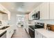 Modern kitchen with white cabinets, stainless steel appliances, and wood-style floors at 3871 Moore St, Wheat Ridge, CO 80033