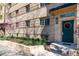 Charming brick building exterior with a teal door, manicured landscaping, and vibrant flowers at 1321 E 10Th Ave # 4, Denver, CO 80218