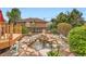 Backyard oasis featuring a tranquil pond with a waterfall, lush greenery, mature trees, and inviting deck at 15325 W 32Nd Ave, Golden, CO 80401