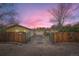 Gated driveway leads to a yellow house, garage, and basketball hoop at sunset at 15325 W 32Nd Ave, Golden, CO 80401