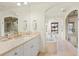 Bright bathroom featuring double vanity, walk-in shower, and a soaking tub beneath a window at 5455 E Cedar Ave, Denver, CO 80246