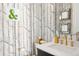 Stylish powder room featuring unique tree-themed wallpaper and gold fixtures at 5455 E Cedar Ave, Denver, CO 80246