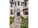 Charming stone-clad home entrance with arched doorway, decorative landscaping, and a welcoming pathway at 5455 E Cedar Ave, Denver, CO 80246