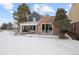 Brick home's patio with sliding glass doors and outdoor seating in snowy backyard at 7079 S Locust Pl, Centennial, CO 80112
