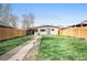 Spacious backyard with a manicured lawn, new fence, and inviting walkway to the home's entrance at 4827 Meade St, Denver, CO 80221