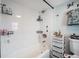 Bathroom with white tiled shower over tub and convenient storage shelving at 4827 Meade St, Denver, CO 80221